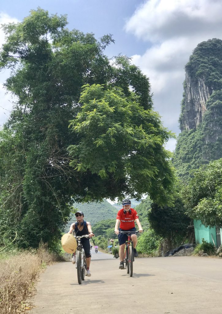 This is a picture of two beautiful and fit looking people riding under a Banyon tree along the back road to the Gaotian water cave  about 15 km from Yangshuo. 
 